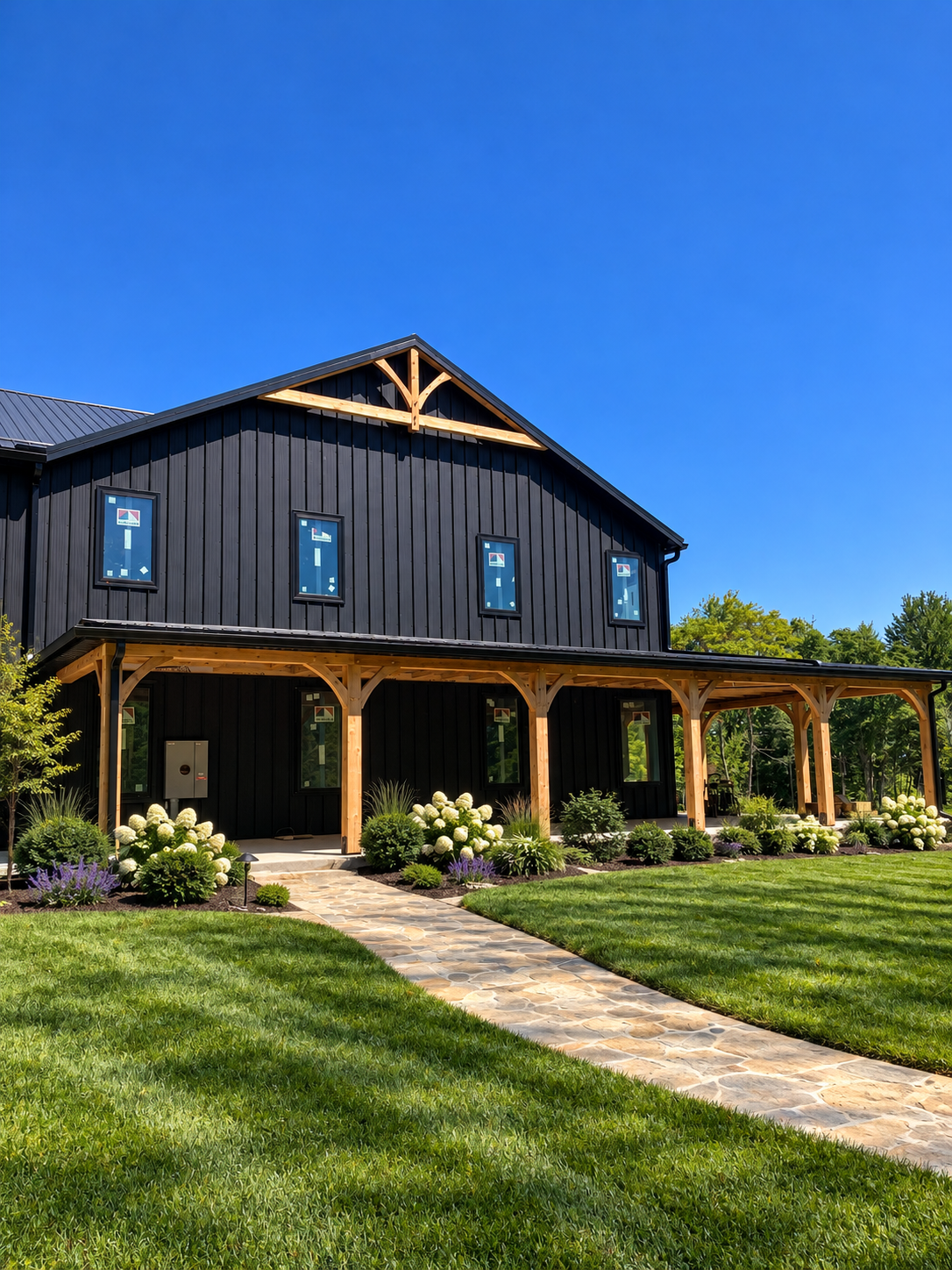 Black barn-style home with timber porch columns, stone walkway and landscaping