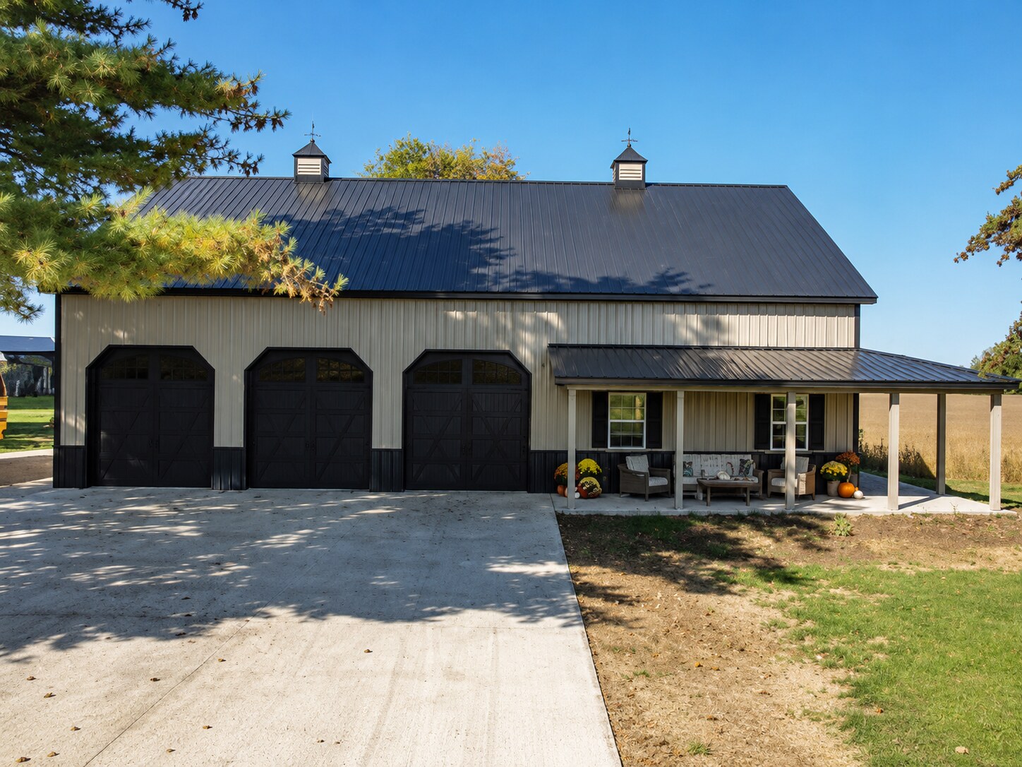 Residential post-frame garage with white metal siding and black roof