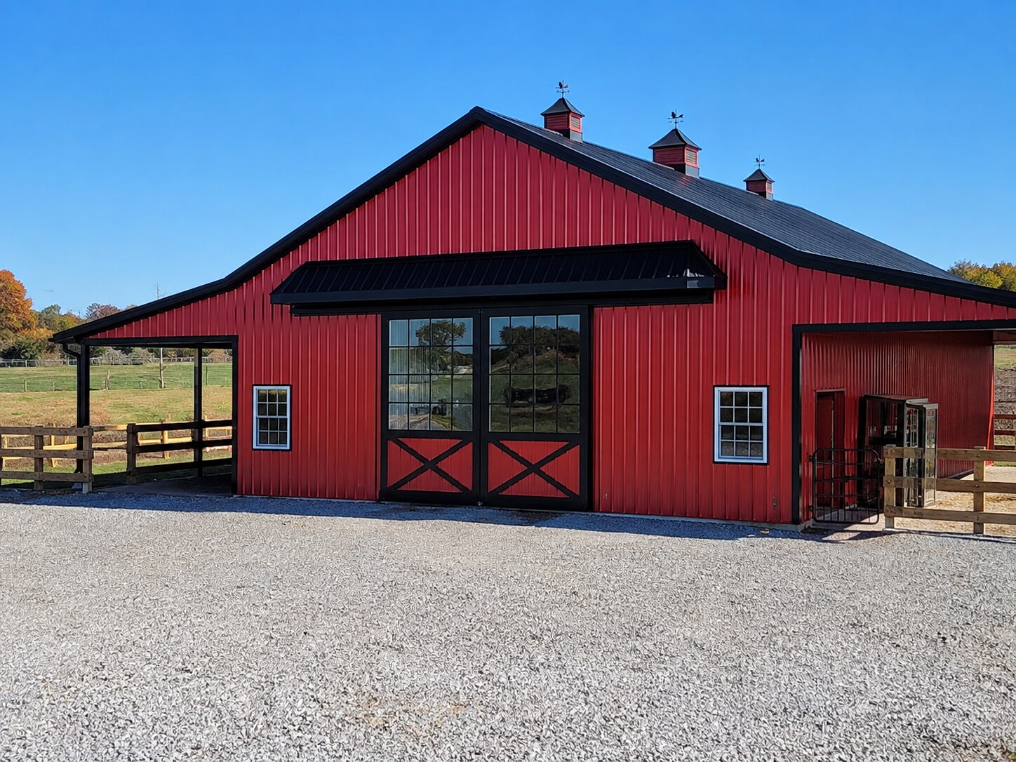 Red barn with black arched entry doors and gravel drive