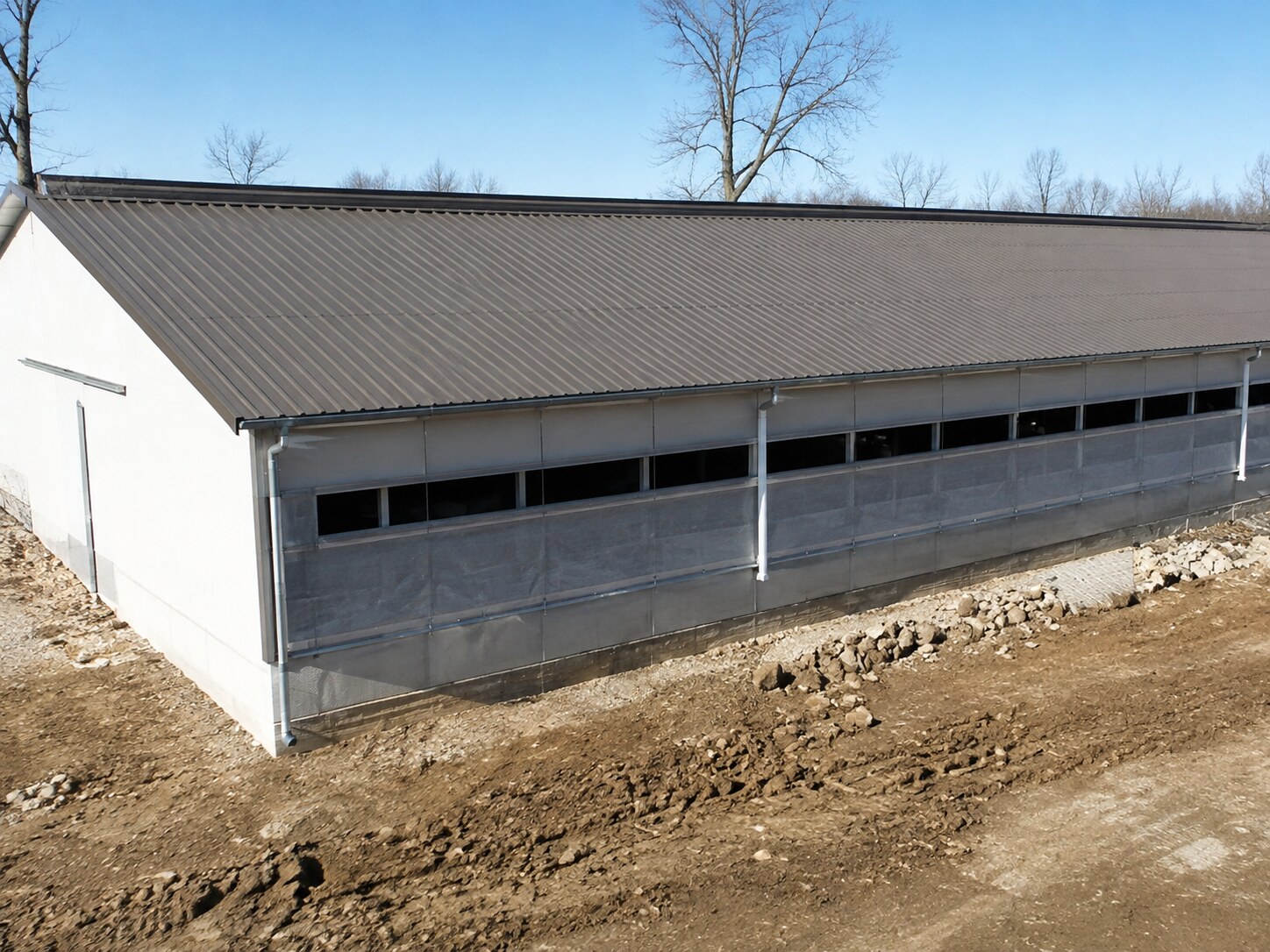 Gray post-frame shop with open lean-to and overhead doors