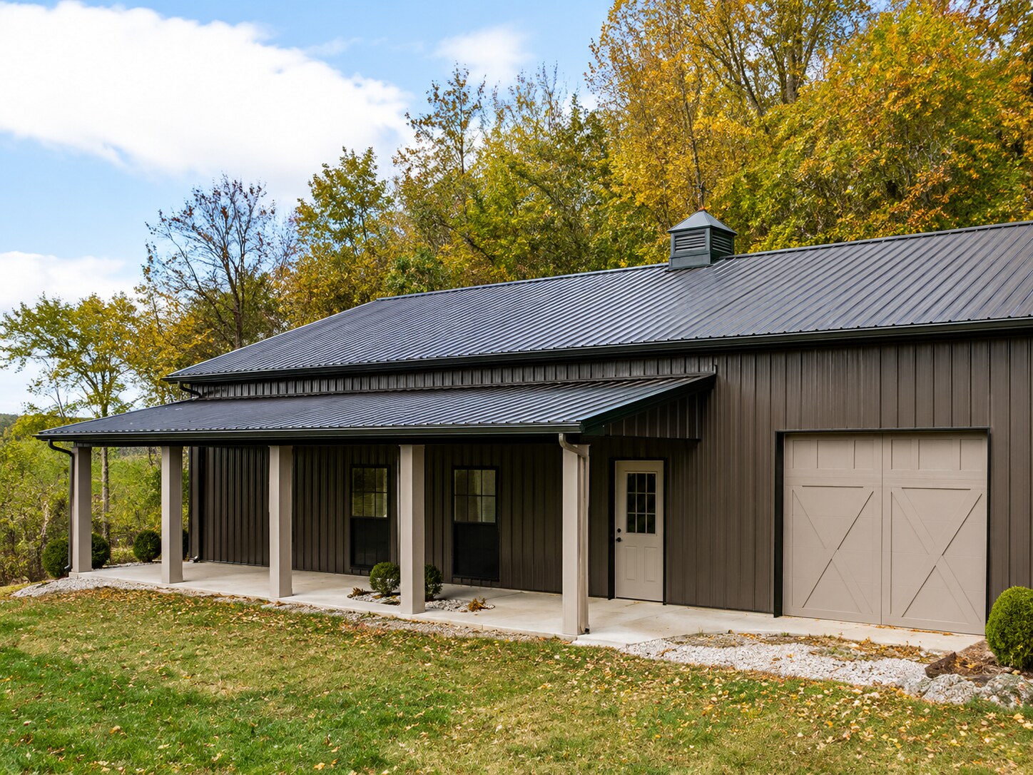 Tan post-frame shop with covered porch and entry door