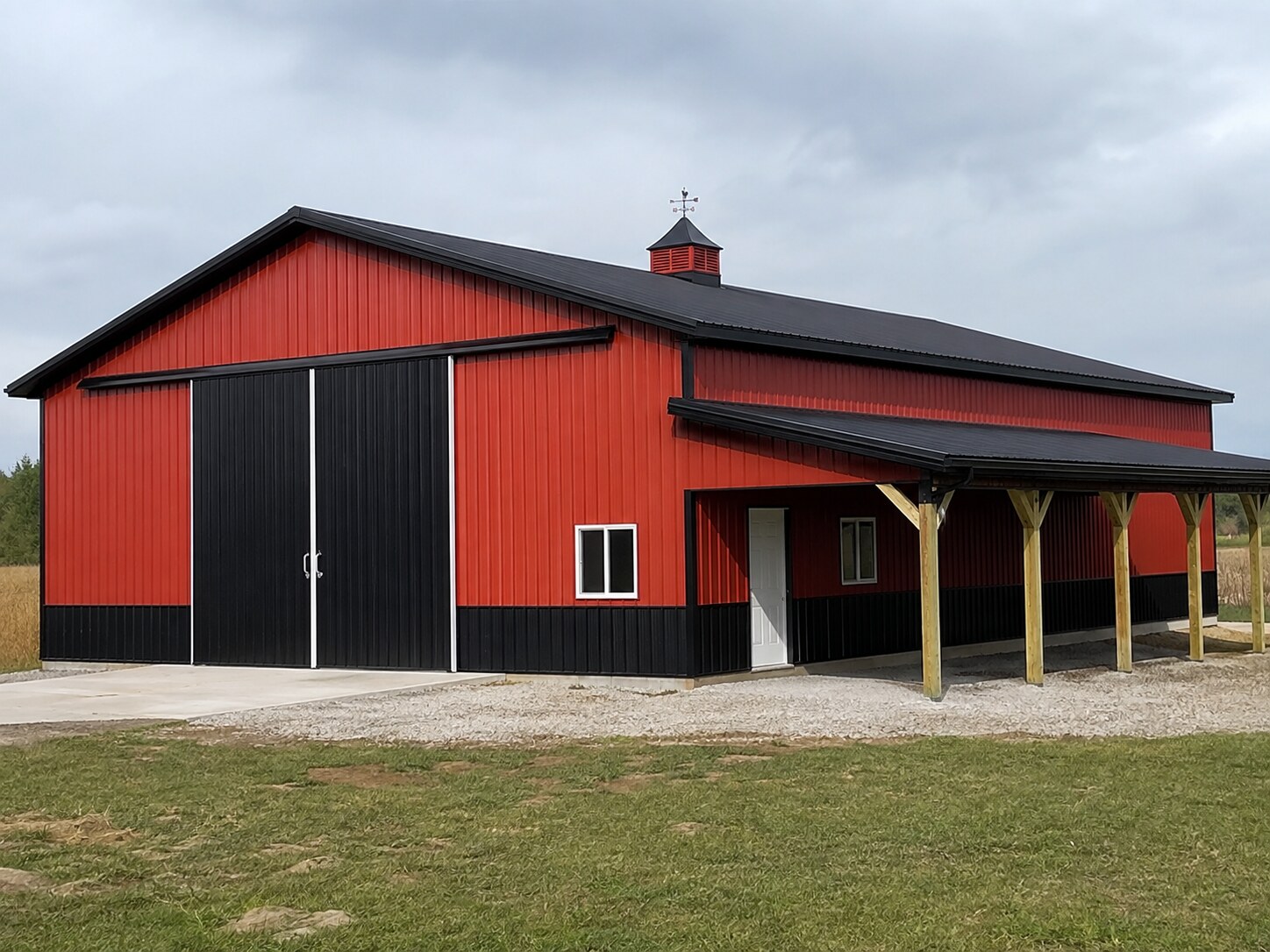 Red barn with black overhead door and covered porch