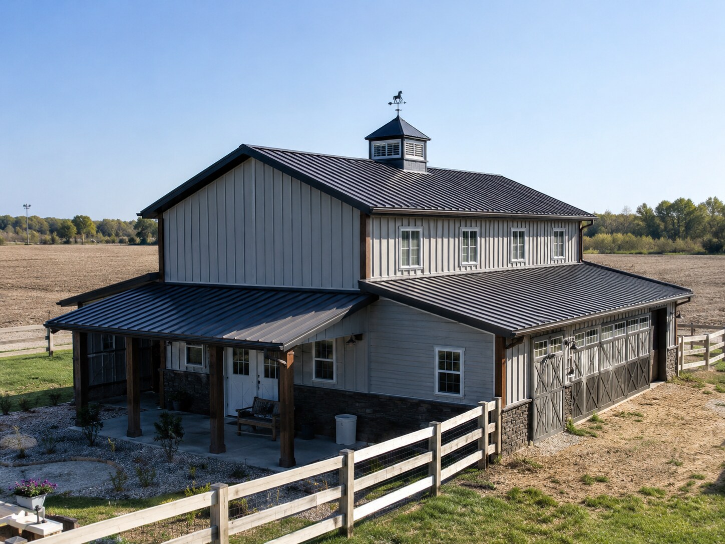 Long white building with red metal roof and equipment parked outside