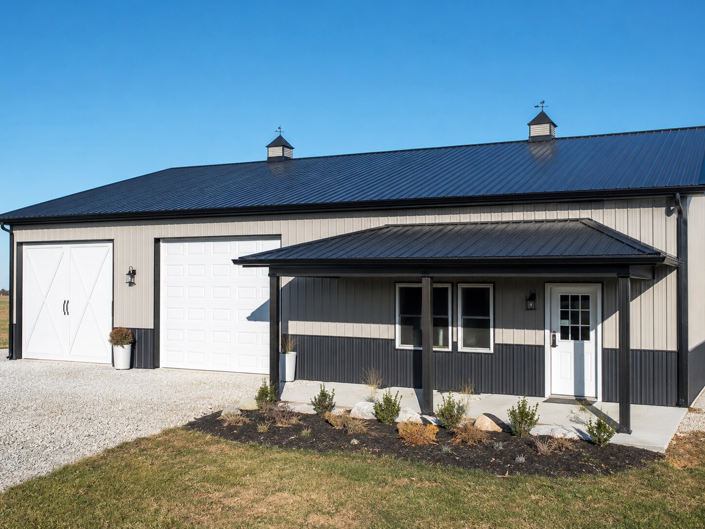 Gray barn with cupola, covered porch and board fencing