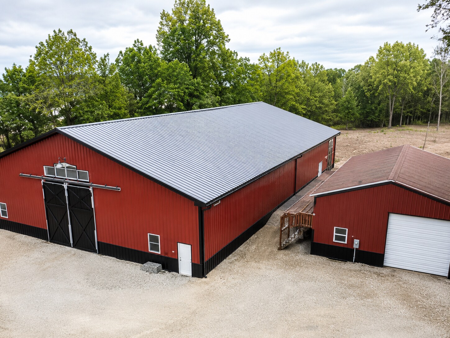 White post-frame garage with two overhead doors and a covered porch