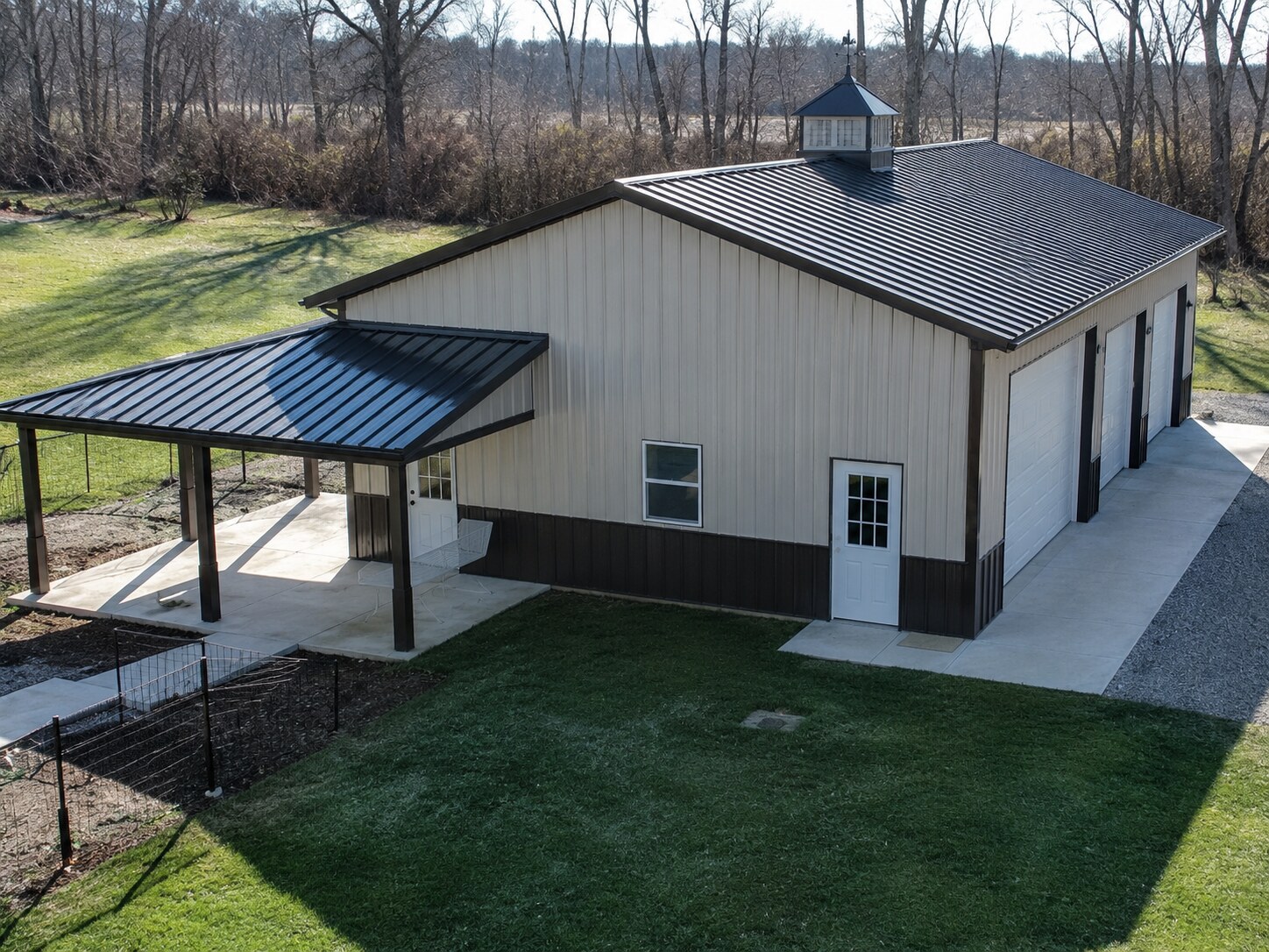 Tan post-frame shop with covered walkway and paved approach