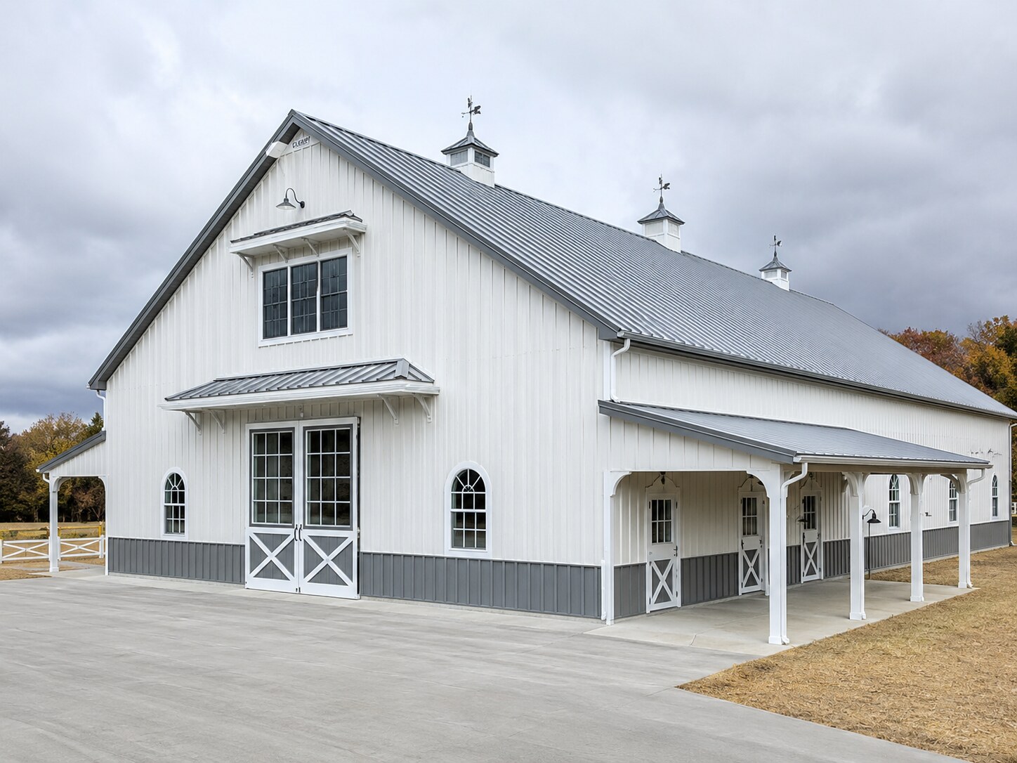 White barn with dormers, cupolas and covered porch