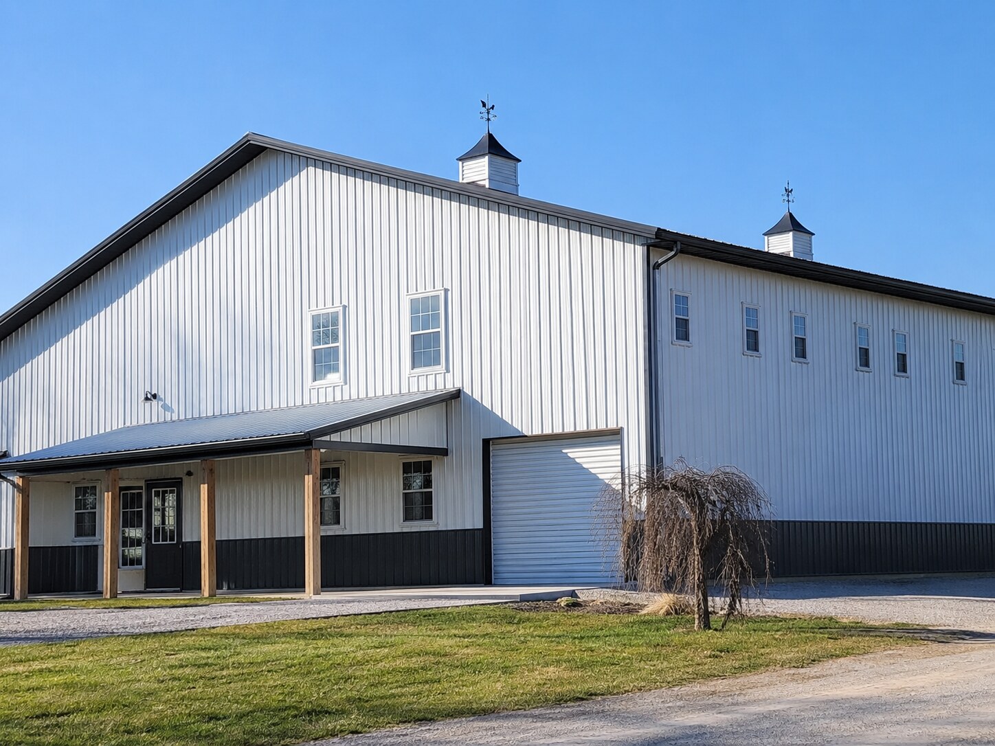 Gray three-car garage with black overhead doors and gravel drive