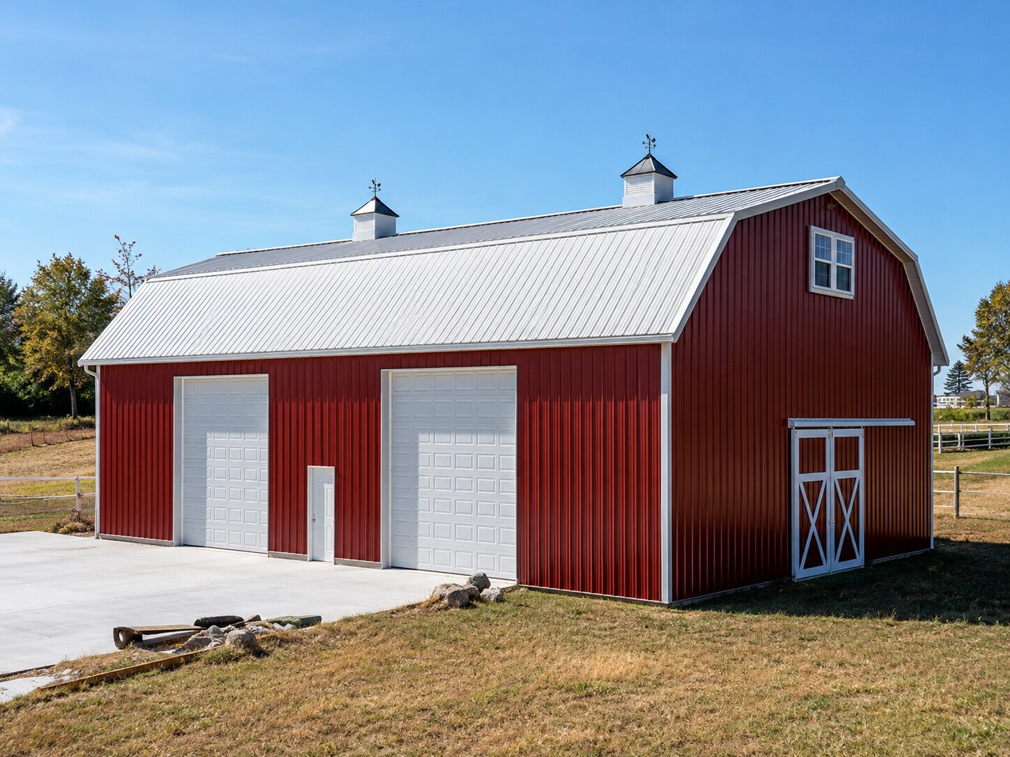 White horse barn with board fencing and dark metal roof