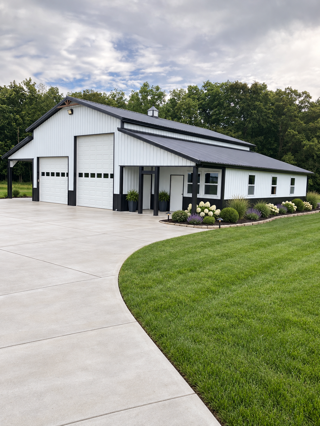 White barn-style building with black trim, two overhead doors and covered porch