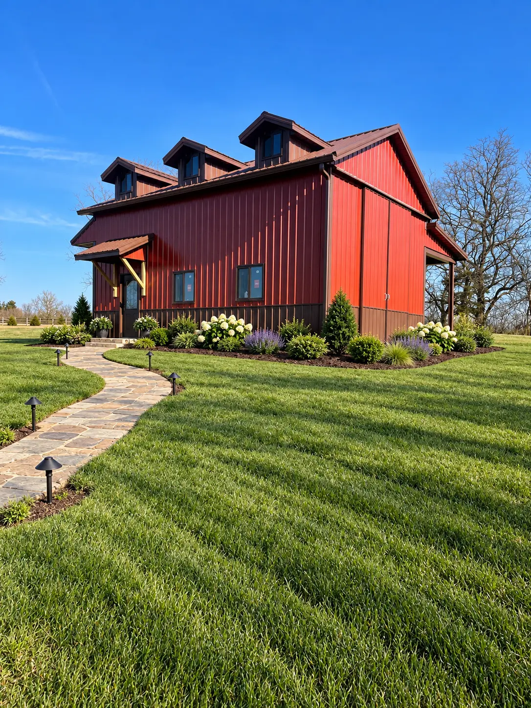 Red monitor barn with brown metal roof, dormers, covered entry and stone walkway