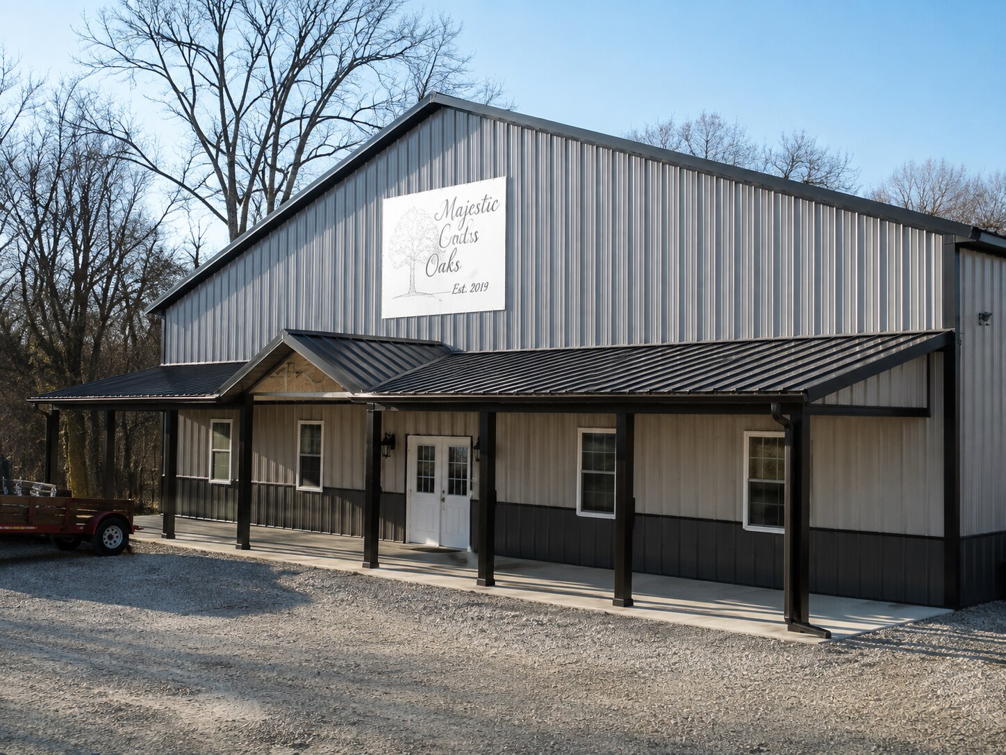 Wide gray post-frame building with covered porch and entry doors
